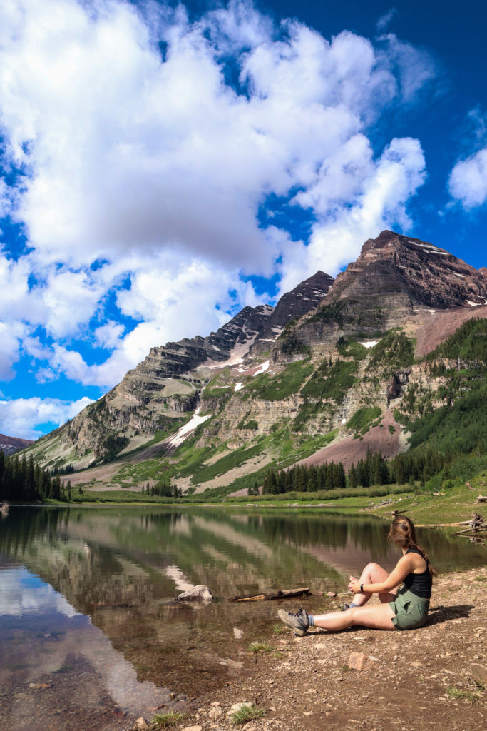 Hiker at Crater Lake in shadow of Maroon Bells